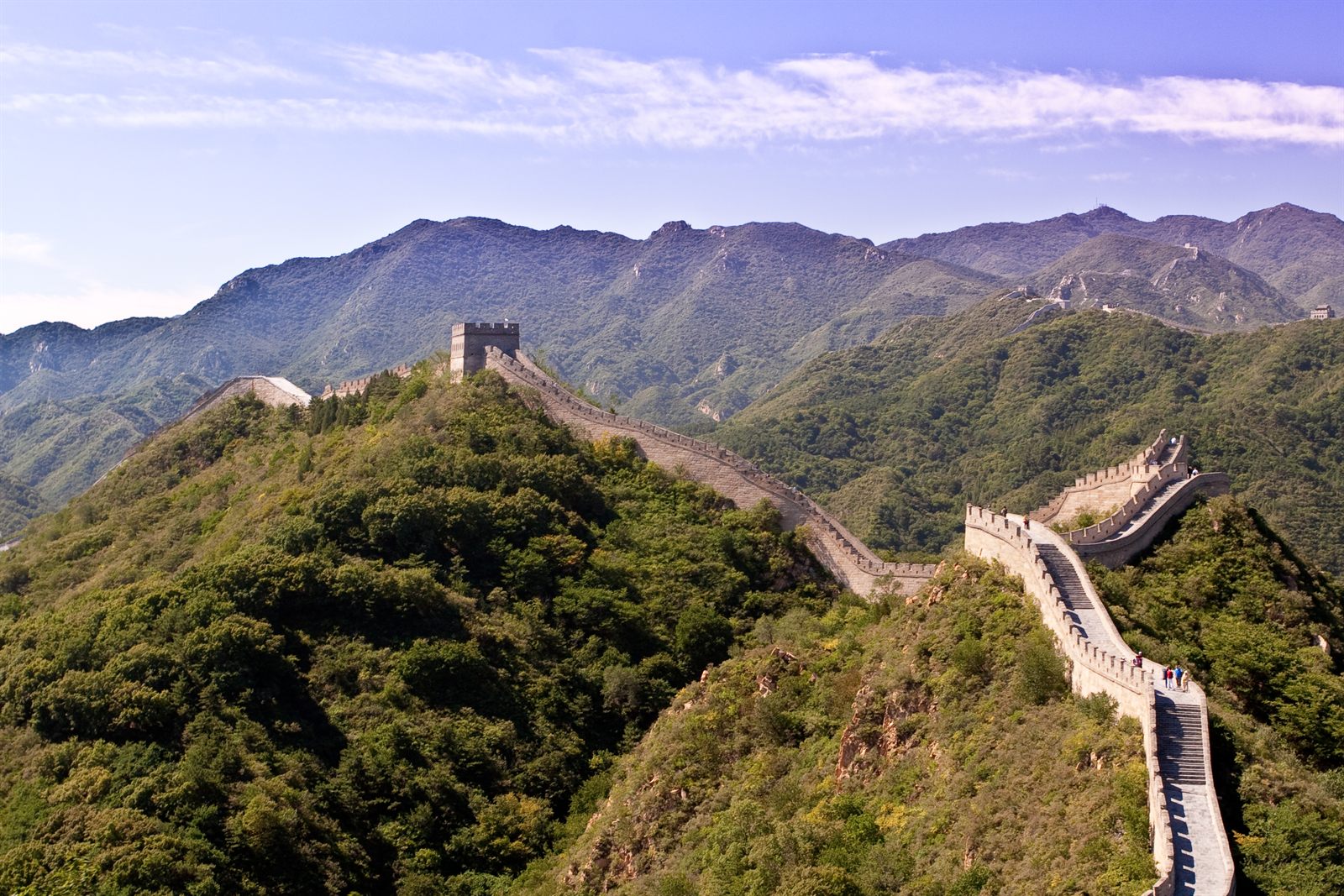 The Great Wall of China winding over green mountain ridges